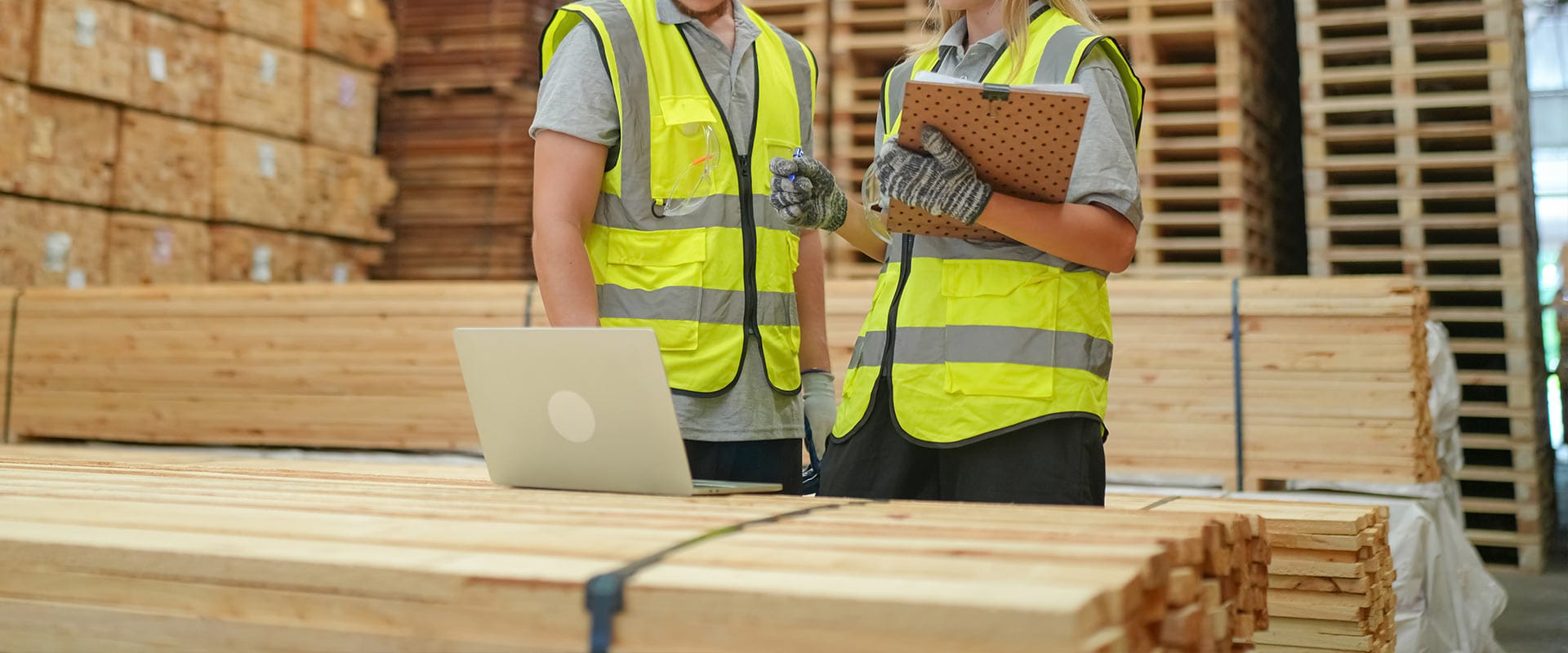 Le personnel de l'entrepôt examine les stocks de bois avec un ordinateur portable